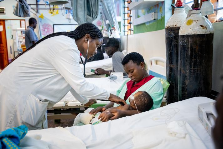 A doctor supports a mother and her child to recieve care